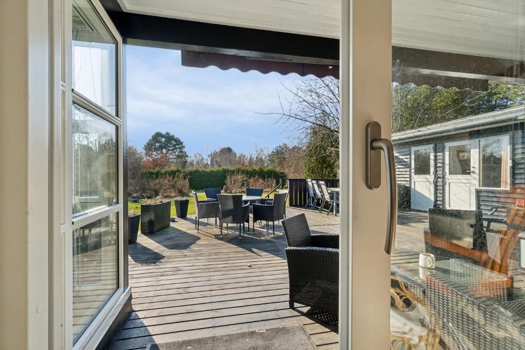 an open door to a deck with chairs and tables at Cozy Cottage Only 500 M From The Sea in Gilleleje