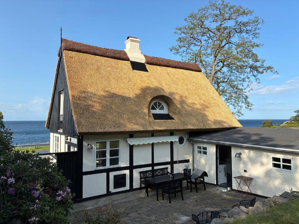 a black and white house with a table in front of it at Cottage With Breathtaking Sea And Cliff Views in Allinge
