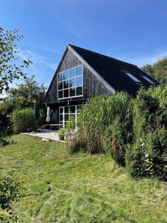 a house with a black roof and some bushes at Lovely Beach Home Enveloped In Green Surroundings in Ebeltoft