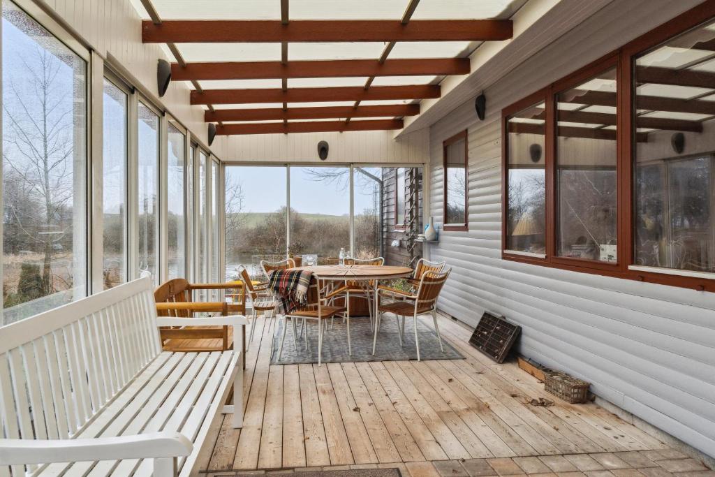 a porch with a table and chairs and windows at Spacious Cottage Surrounded By Forest in Mesinge