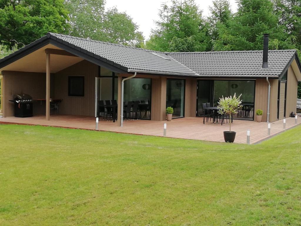 a house with a large deck with tables and chairs at Charming Cottage In Fjellerup With Indoor Spa in Glesborg