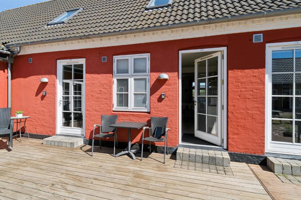 a red building with a table and chairs on a deck at Holiday Apartment For 4 With Shared Pool in Åkirkeby