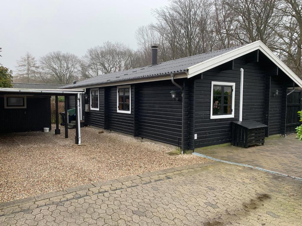 a small black house with a driveway in front of it at Experience The Forest And Sea in Ålsgårde