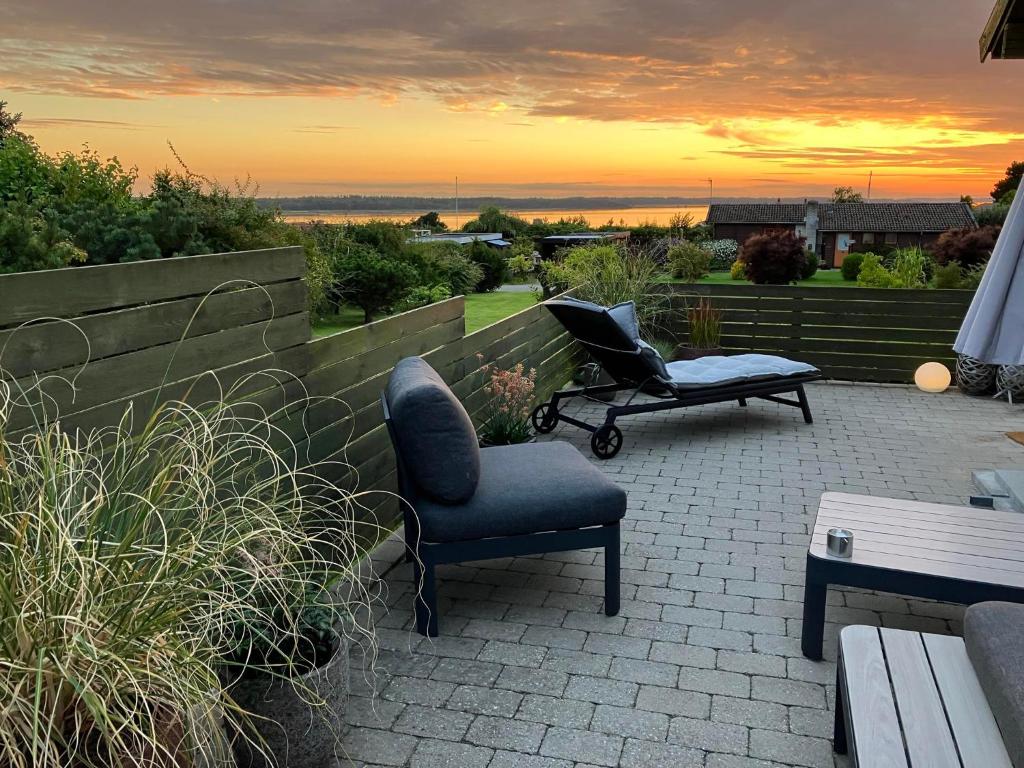 a patio with a chair and a bench and a sunset at Cozy Summerhouse With Spectacular Views in Ølsted