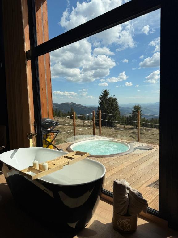 a bath tub in a room with a view of a pool at Ascent Lodge -Jacuzzi si Panoramic View in Petreasa