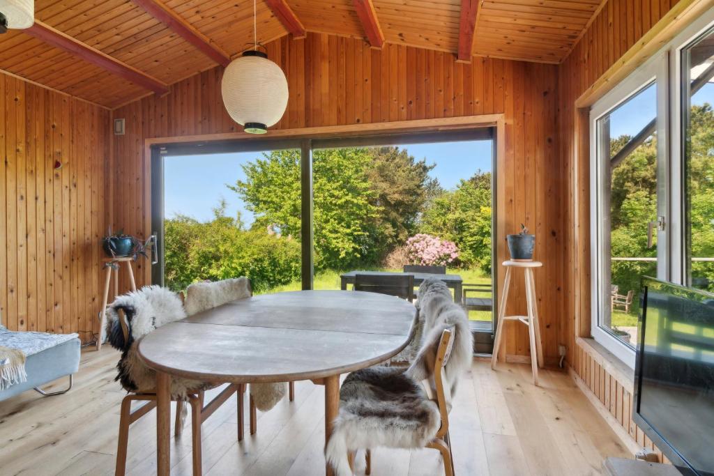 a dining room with a table and a large window at Romantic Retreat Close To The Beach in Fårevejle