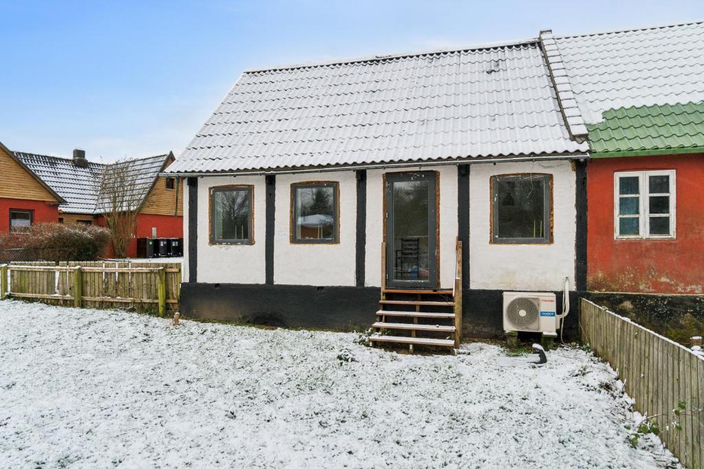 a small white house with a snow covered yard at Cosy House Near Forest in Rønne
