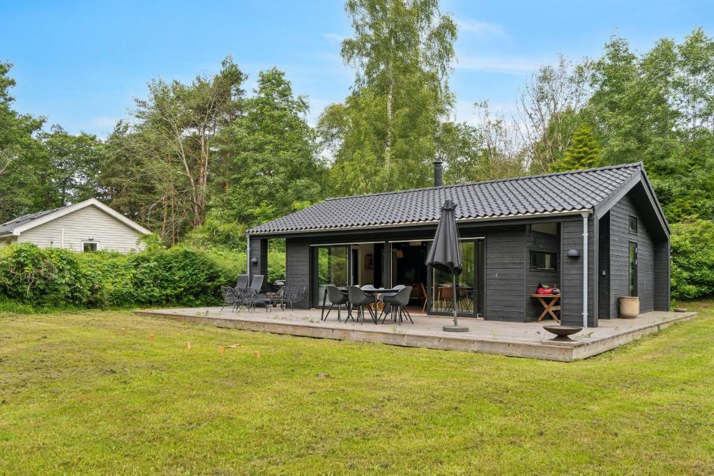 a black cottage with a patio and an umbrella at Scenic Summer House In Asserbo in Frederiksværk