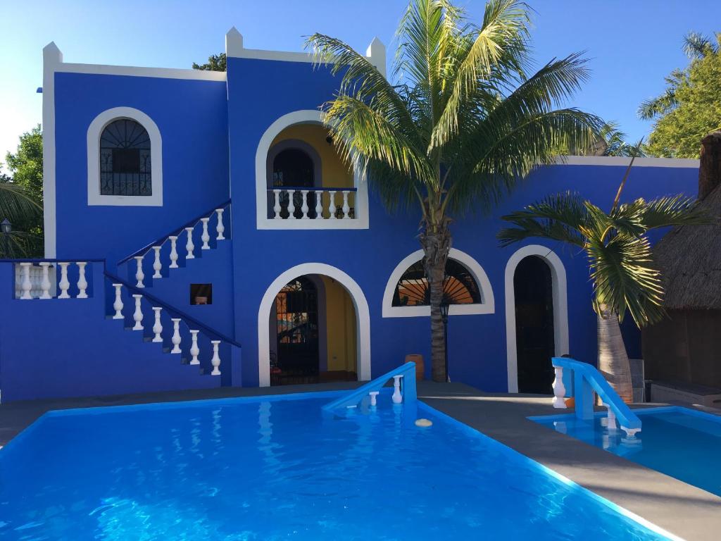 a blue house with a swimming pool and a palm tree at Hacienda San Pedro Nohpat in M&eacute;rida