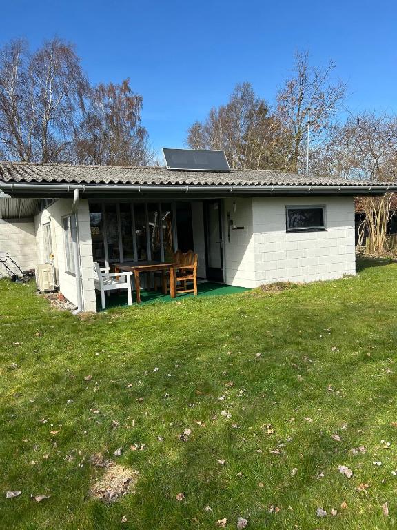 a small white house with a green yard at Cozy Cottage Near Bjerge Strand in Store Fuglede
