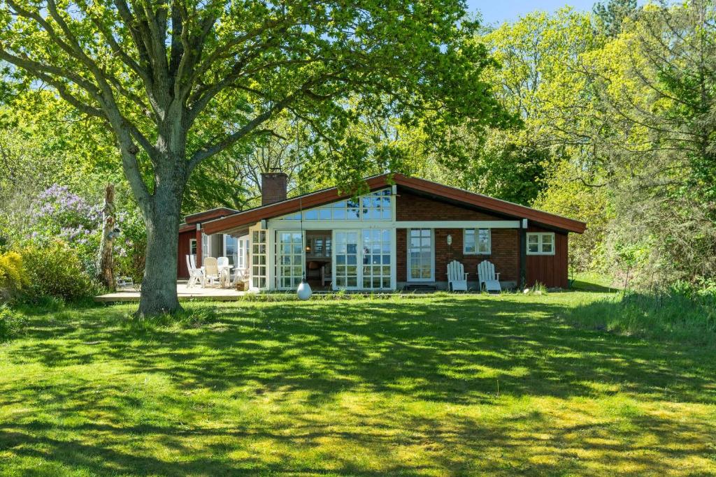 a house in a yard with a tree at Togetherness Coziness Magical Great Belt View in Tranekær