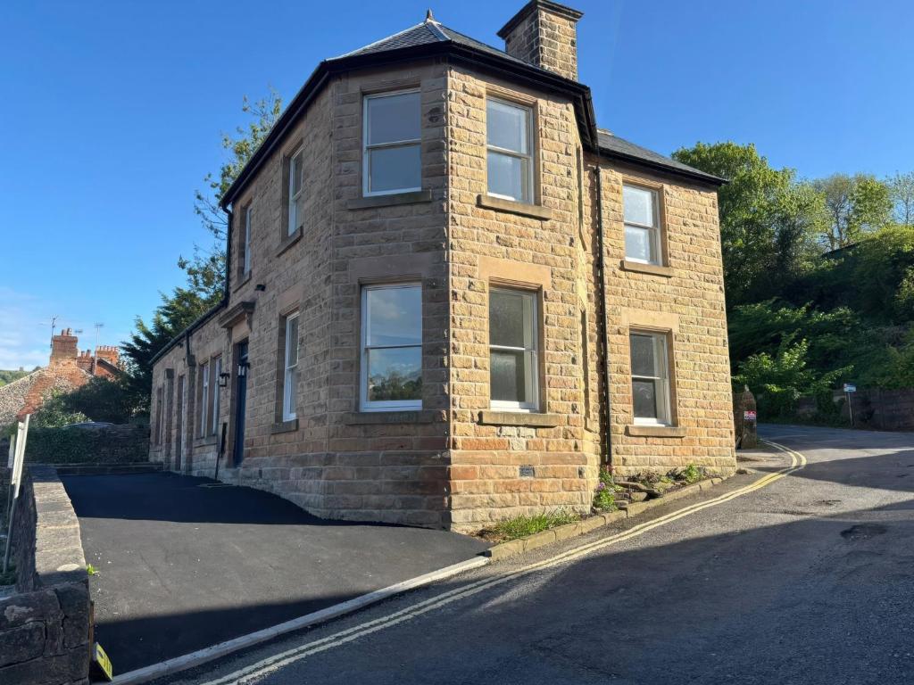 a brick house on the side of a street at Holt Hall - First Floor Apartment in Matlock