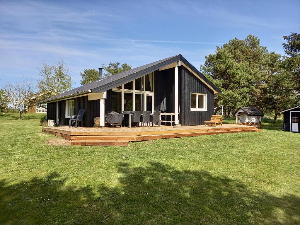 a black house with a large deck in a field at Holiday Home Near Hvalpsund in Farsø