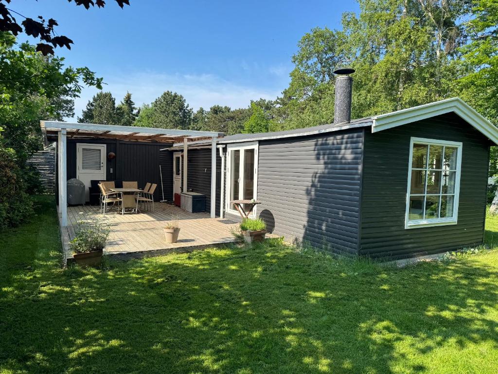 a small house with a wooden deck in a yard at Holiday Home Near Nordstrand Nykøbing Sj in Nykøbing Sjælland