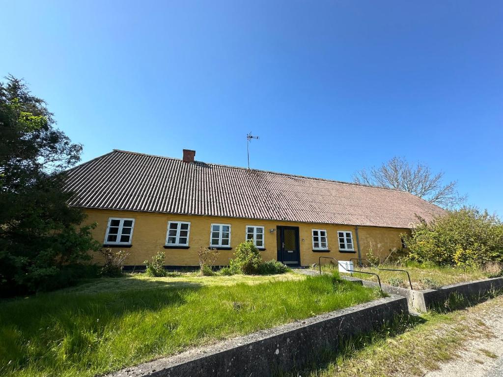 a yellow house with a grassy yard in front of it at Cozy Older Property On Ærø in Søby