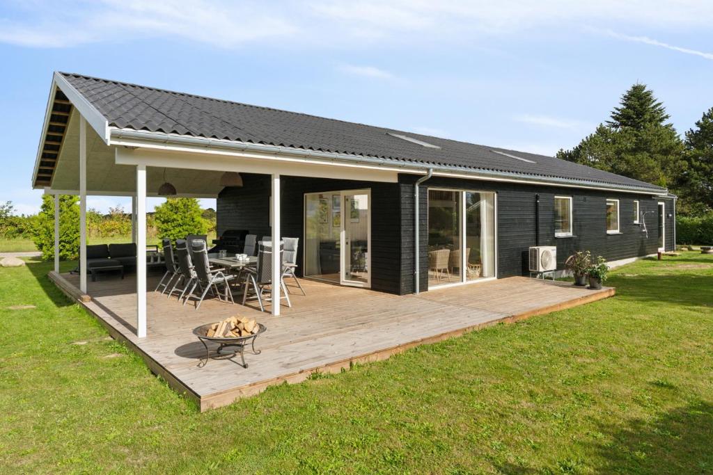 a black house with a deck with a grill at Spacious Holiday Home On Bogø in Bogø By