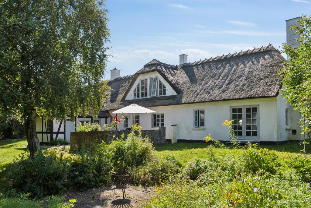 a white house with a gray roof at Idyllic Half-Timbered House For 10 Guests in Kettinge