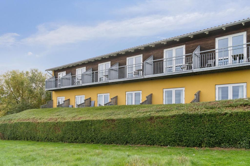 a yellow building with balconies on top of a hedge at Pension Koch Apartment 6 in Gudhjem