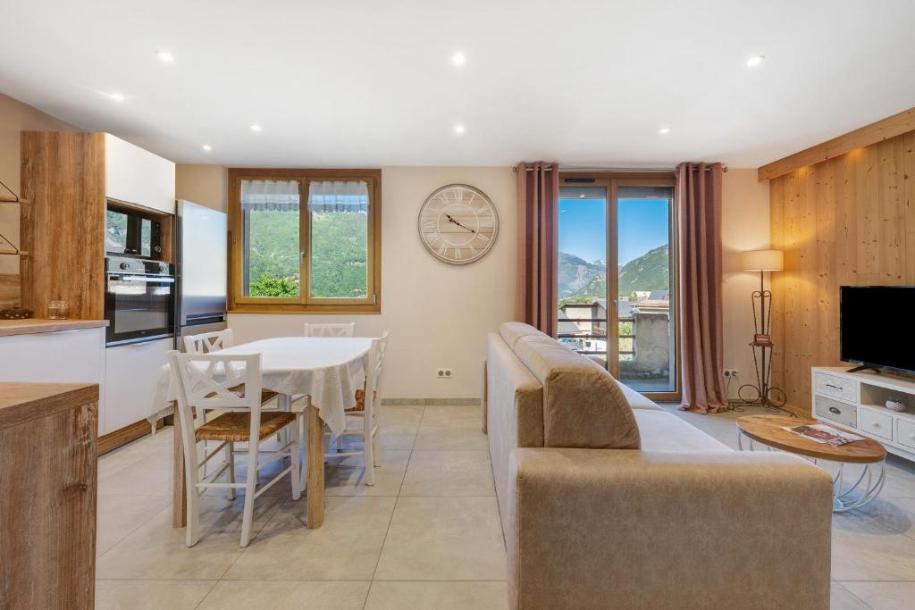 a kitchen and living room with a table and a clock on the wall at Maison "Casabert" in Saint-Martin-de-la-Porte