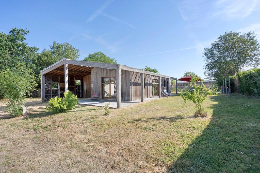 a wooden house in a field with a yard at Gite Le Koto in Thorigny