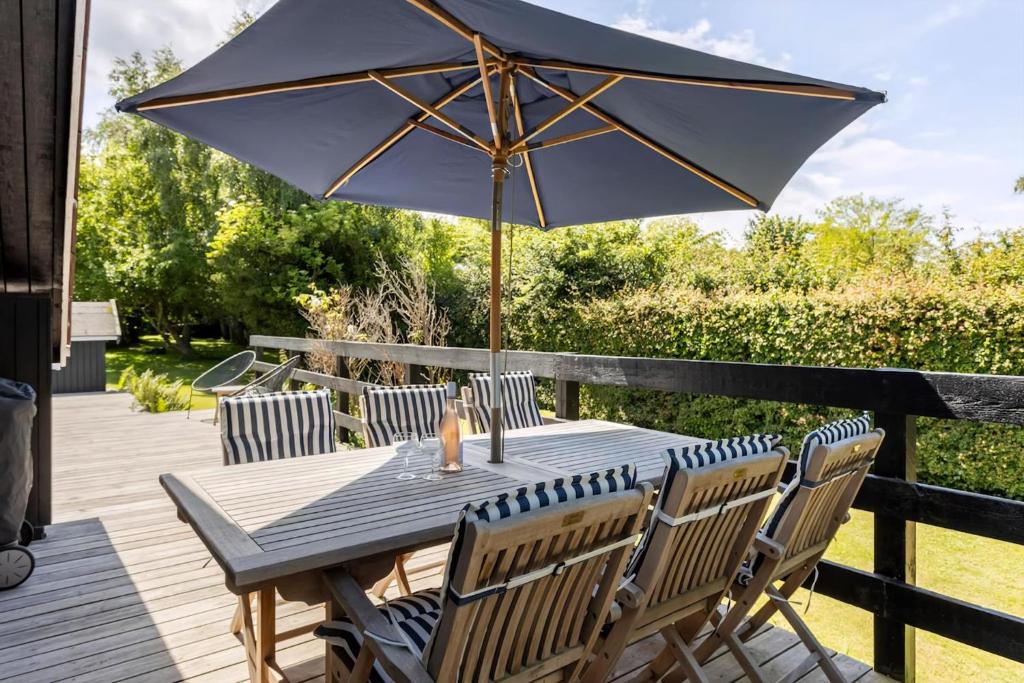 a wooden table with an umbrella on a deck at Idyllic Summer House Close To Beach And Forest in Tisvildeleje