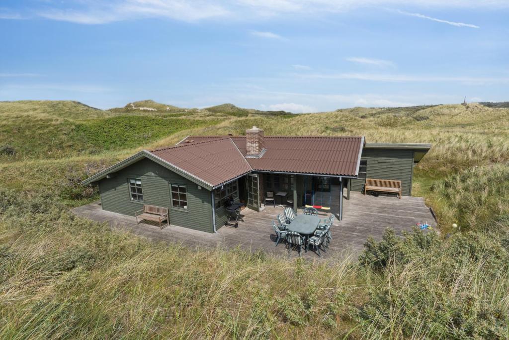 a house with a deck in the middle of a field at Summerhouse In Peaceful Surroundings in Pandrup