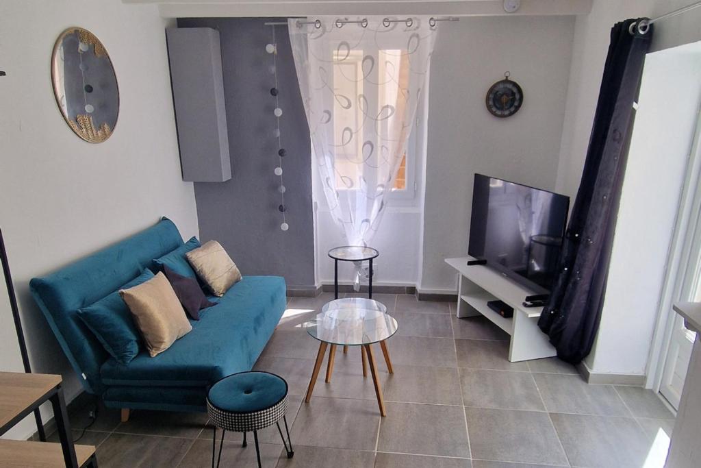 a living room with a blue couch and a tv at Marguerite - Charme et confort in Orange