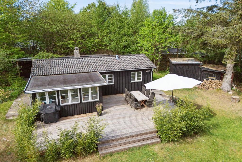a wooden deck with a house and an umbrella at Cozy Holiday Home in Nyrup