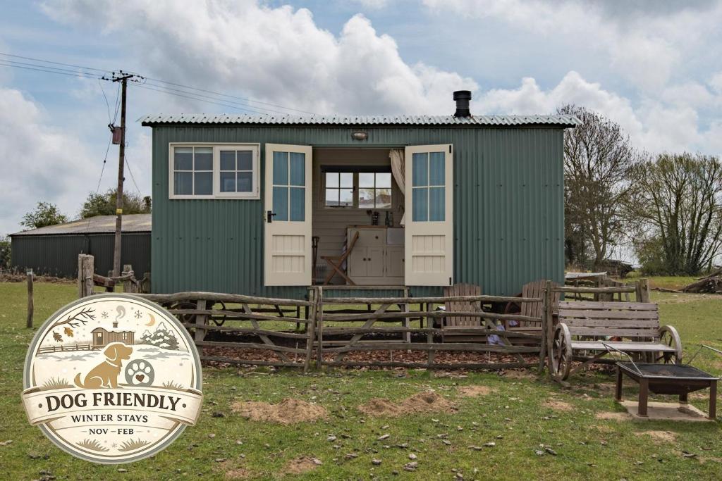 a green tiny house with a sign in front of it at Rumwold by Bloom Stays in Ashford
