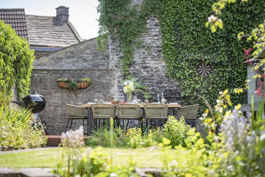 a table and chairs in a garden next to a stone wall at The Old Manse in Leyburn