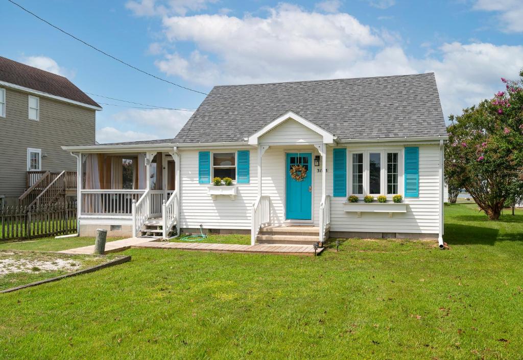 a white house with a blue door and a yard at Bertie Street Cottage in Chincoteague