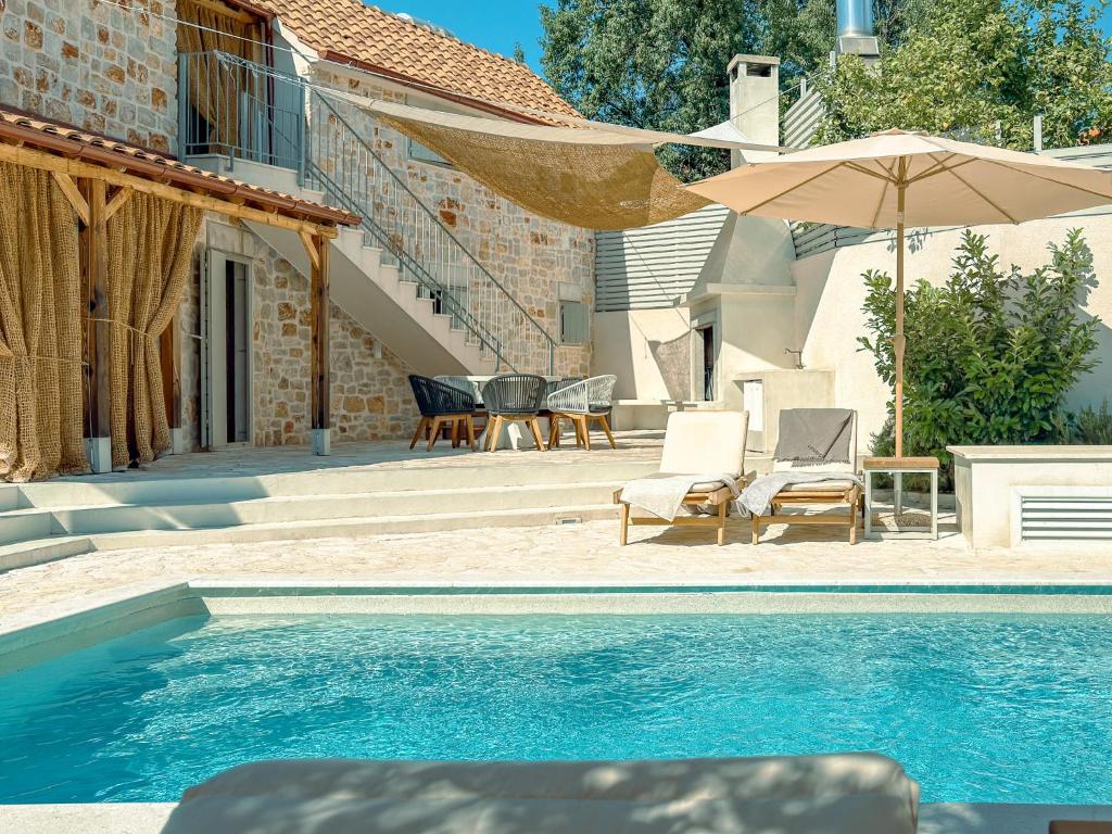 a pool with chairs and an umbrella next to a house at Dolce Terra in Stari Grad
