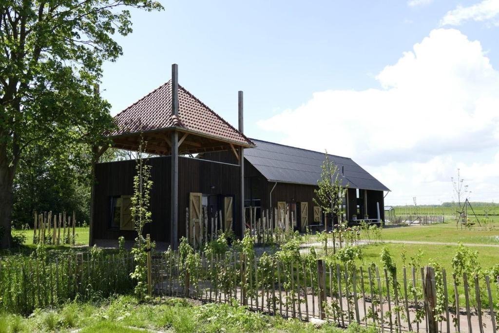 a black barn with a fence in front of it at Lennepserf - De Bok in Veessen