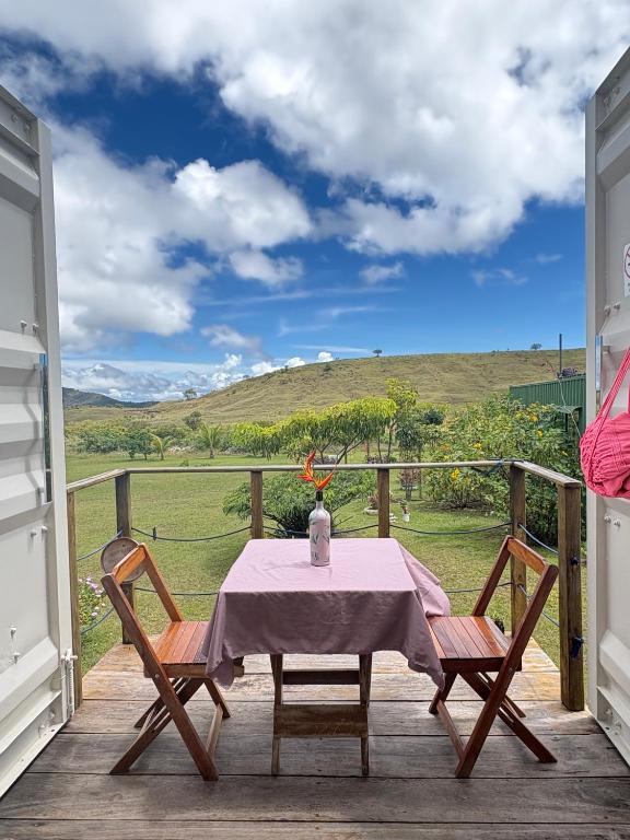 a table and chairs on a deck with a view at Pousada Mão de Deus in Vila Tepequém