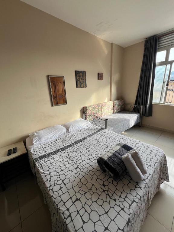 a bedroom with a bed and a couch and a window at Suítes São Lourenço in São Lourenço