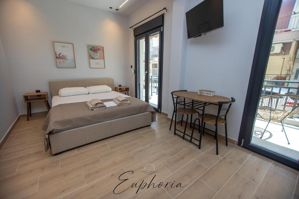 a bedroom with a bed and a table and a balcony at Euphoria Central Living in Stavros