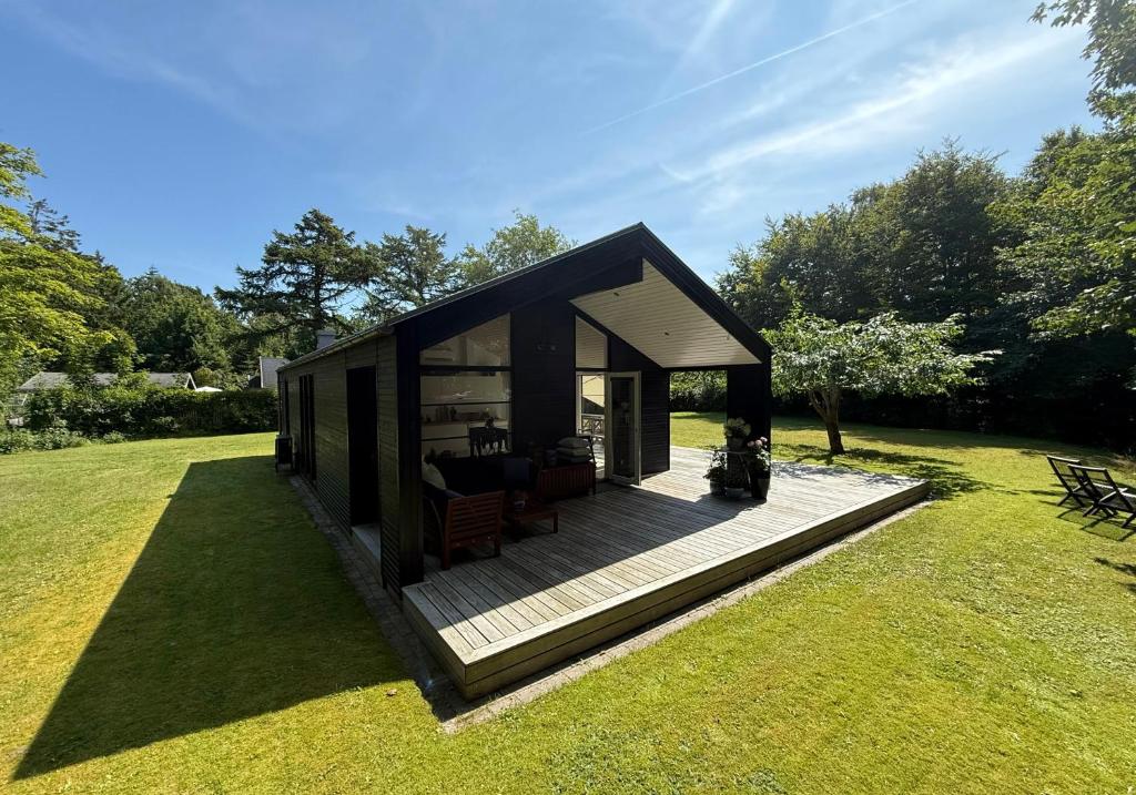 a small house with a deck in the grass at Modern And Stylish Summer Cabin in Vejby