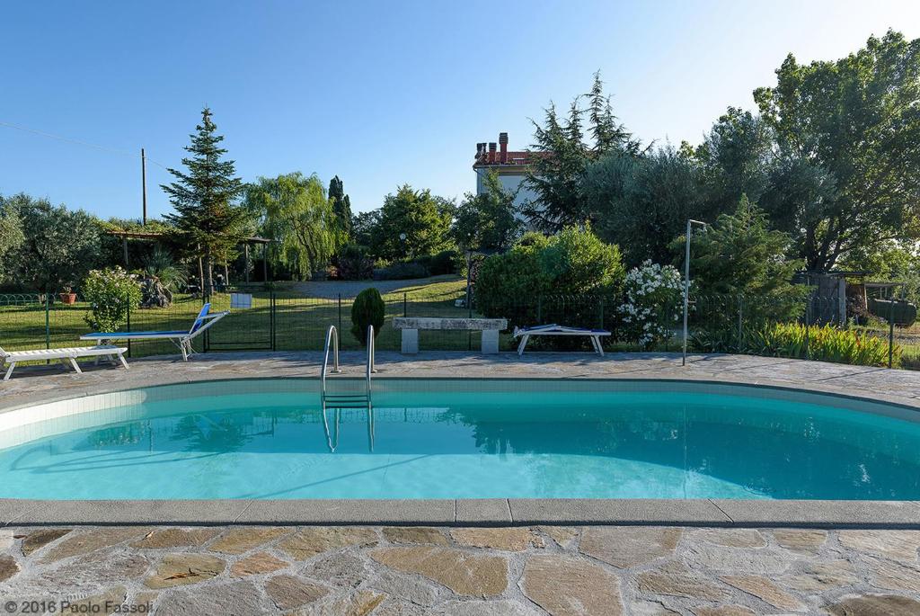 a large swimming pool in a yard with a bench at Appartamenti Poggio Rineschi in Montenero