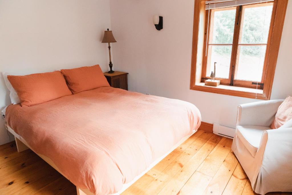 a bedroom with a bed and a chair and a window at Triangle de l'Île Chambre La Yogi in Saint-Laurent-de-l'ile d'Orleans