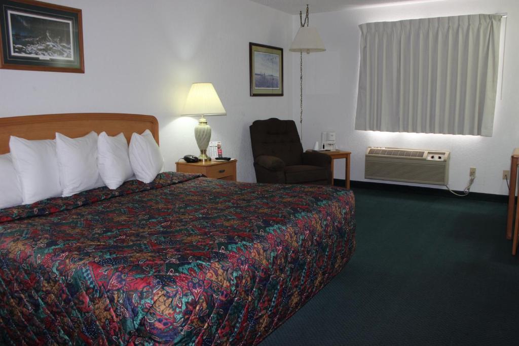 a hotel room with a bed and a chair at Americas Best Value Inn Grand Forks in Grand Forks