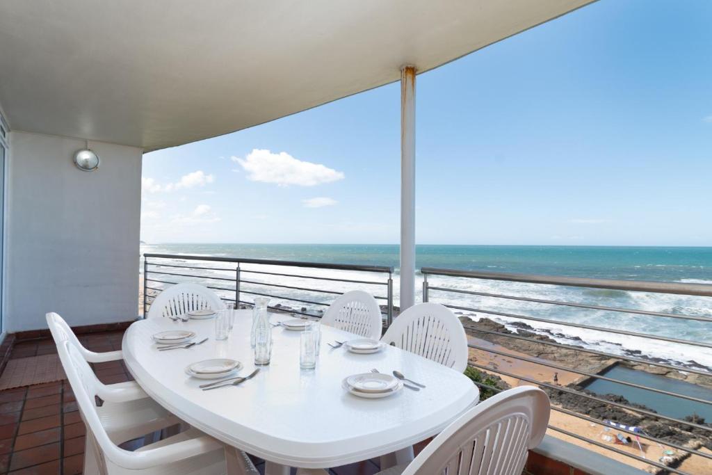 a white table and chairs on a balcony with the ocean at Chakas Cove 34 in Ballito