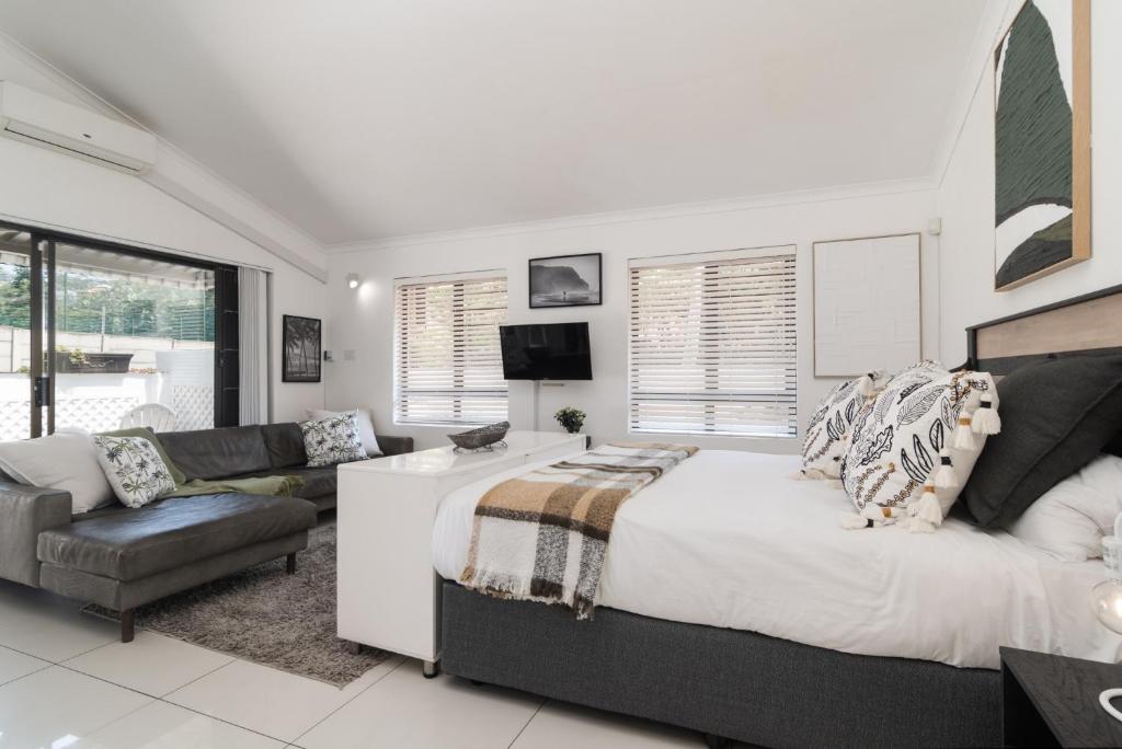a bedroom with a large bed and a living room at La Mer 14 in Ballito