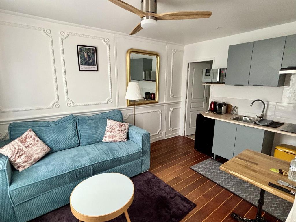 a living room with a blue couch and a kitchen at L'Atelier des Rêves Amboise in Amboise