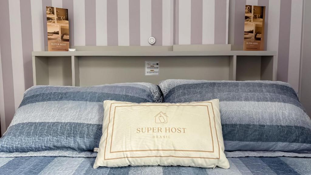 a bed with two blue pillows with a sign on it at SHB - Central Miramar Shopping Mall from the beach in Santos