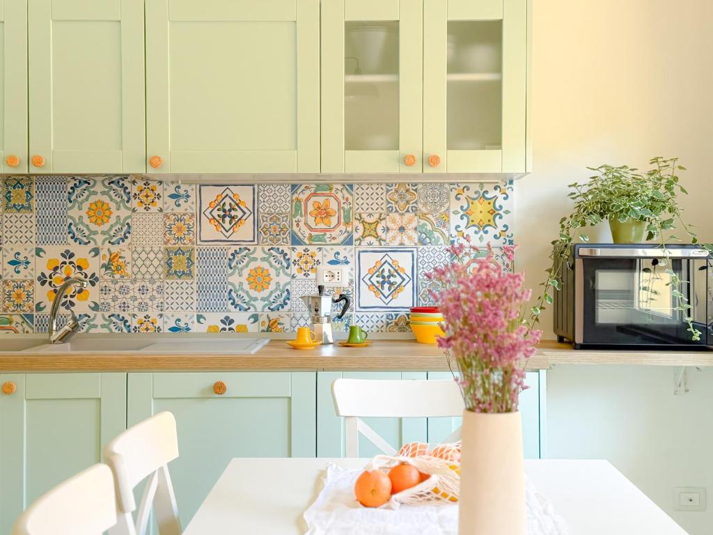 a kitchen with a table with a vase of flowers at Piazza 49 - HelloElba in Portoferraio