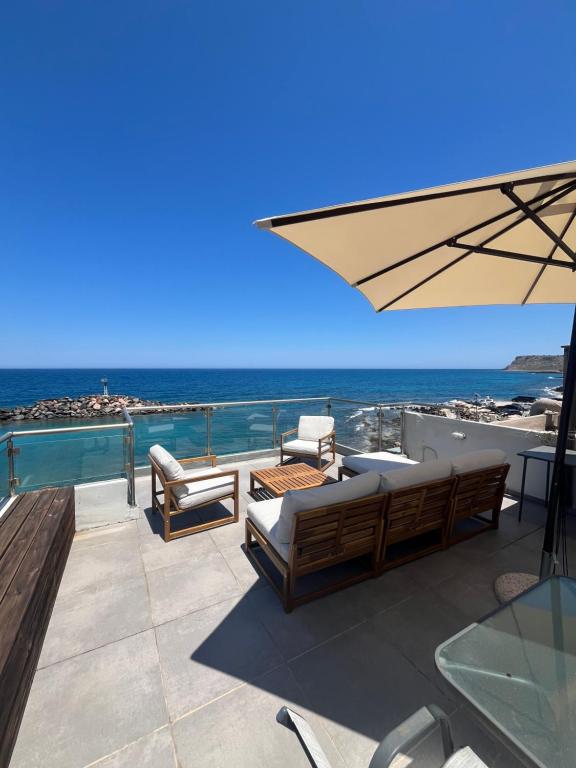 a patio with chairs and an umbrella and the ocean at Oceanview Vega in Sisi