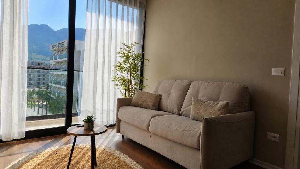 a living room with a couch and a large window at Palm Apartments Radhime in Vlorë