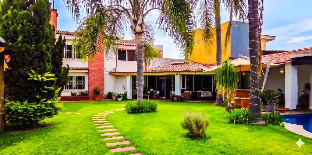 a house with palm trees and a yard at Private Villa in Guadalajara with heated Swimming Pool in San Agustín