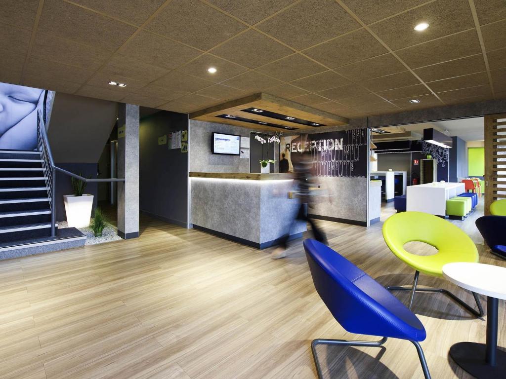 a person walking through an office with chairs and tables at ibis Budget Pau Est in Pau