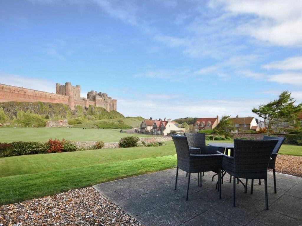 a patio with a table and chairs and a castle at Northrawe in Bamburgh